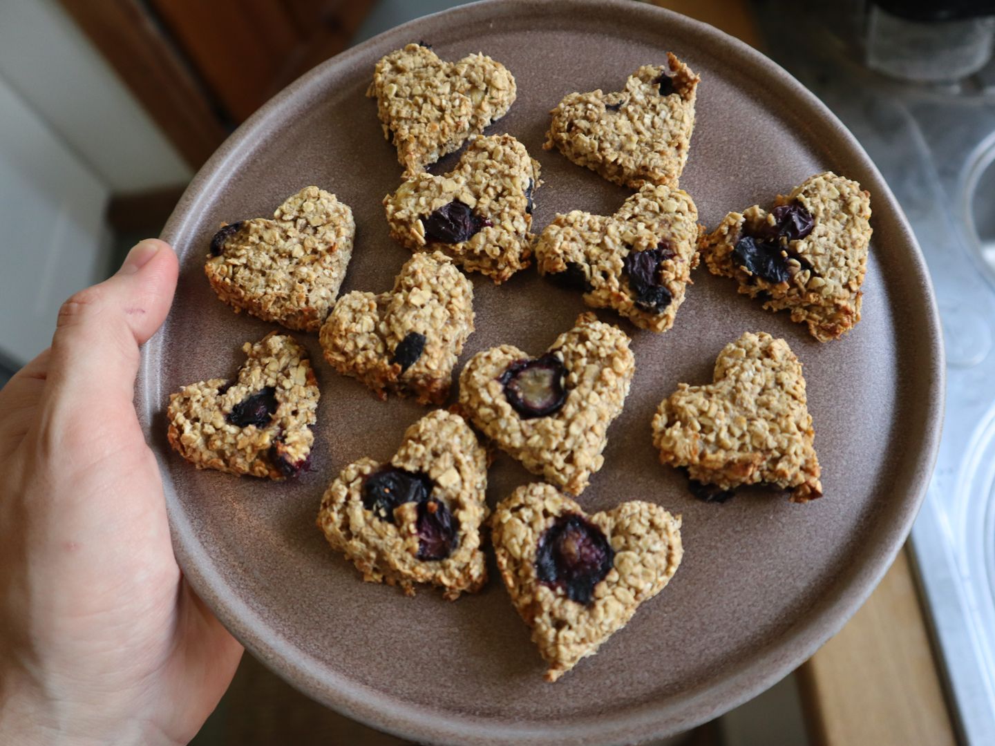 A plate with lots of heart-shaped berry oat biscuits on it