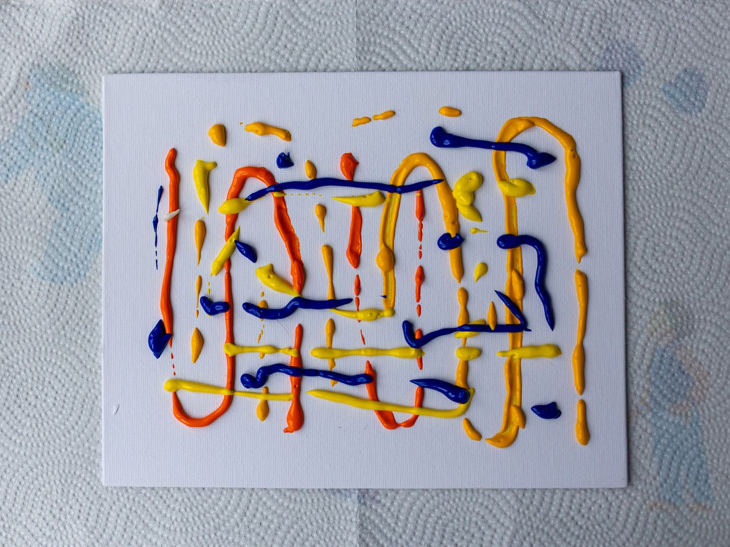 a white canvas with red, blue and yellow paint squiggled all over it